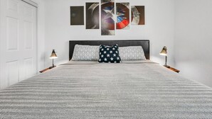 A bedroom with a bed, two bedside lamps, a ceiling fan, and a wall with a large abstract painting. - Cinema: 2 Bedroom, Walk to A&M, Comfy King Beds (Bryan)