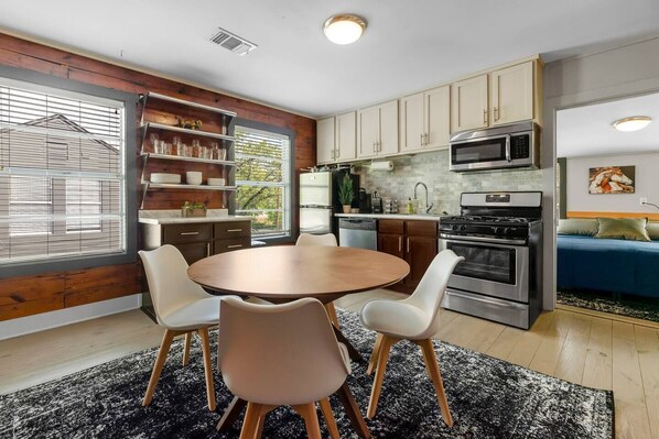 A modern kitchen with a round dining table, white chairs, and built-in appliances.