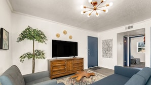 A modern living room with a flat-screen TV, wooden cabinet, two sofas, and a ceiling light fixture. - Elise: 2 Bdrm,  Walk to A&M, Comfy King Beds (Bryan)