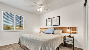A bedroom with a bed, a nightstand, a ceiling fan, a window with blinds, and two framed pictures on the wall. - Elise: 2 Bdrm,  Walk to A&M, Comfy King Beds (Bryan)