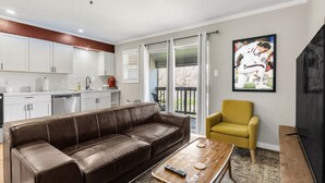 A modern living room with a brown leather sofa, a wooden coffee table, and a yellow armchair. - The Zone: Blocks from Texas A&M, Comfy King Bed (Bryan)
