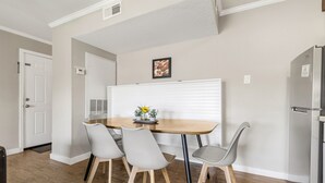 A dining area with a wooden table and four chairs, a white door, and a refrigerator. - The Zone: Blocks from Texas A&M, Comfy King Bed (Bryan)