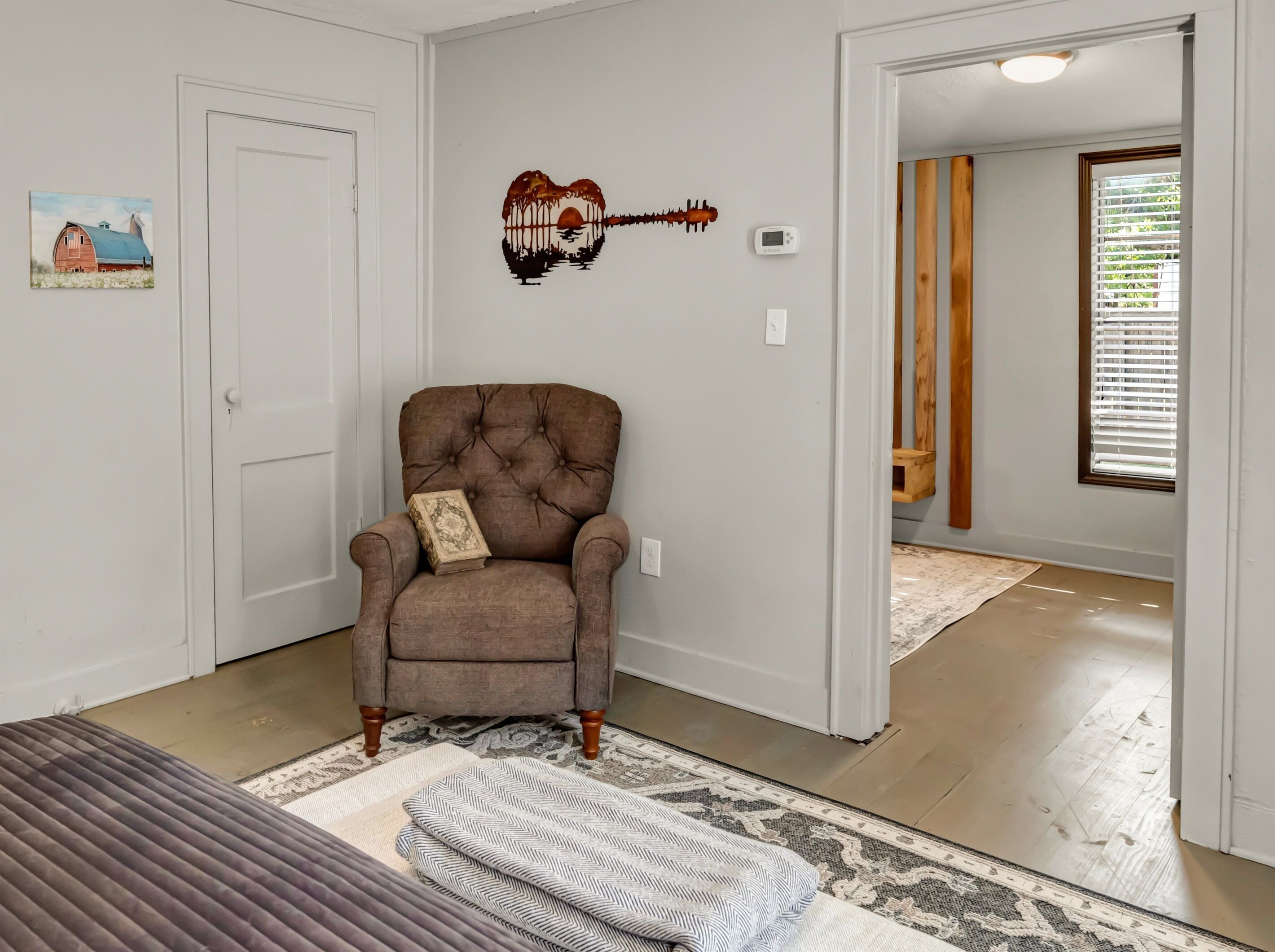 A room with a tufted armchair, a rug, and a wall-mounted guitar decoration.
