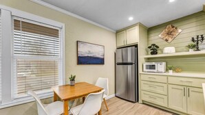 A compact kitchen with a stainless steel refrigerator, a microwave, and a dining table with chairs.
