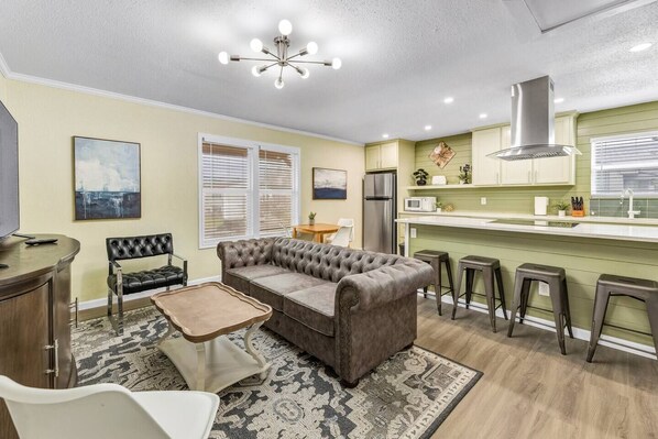 A compact living space with a sofa, a dining table, a kitchen area, and a TV.