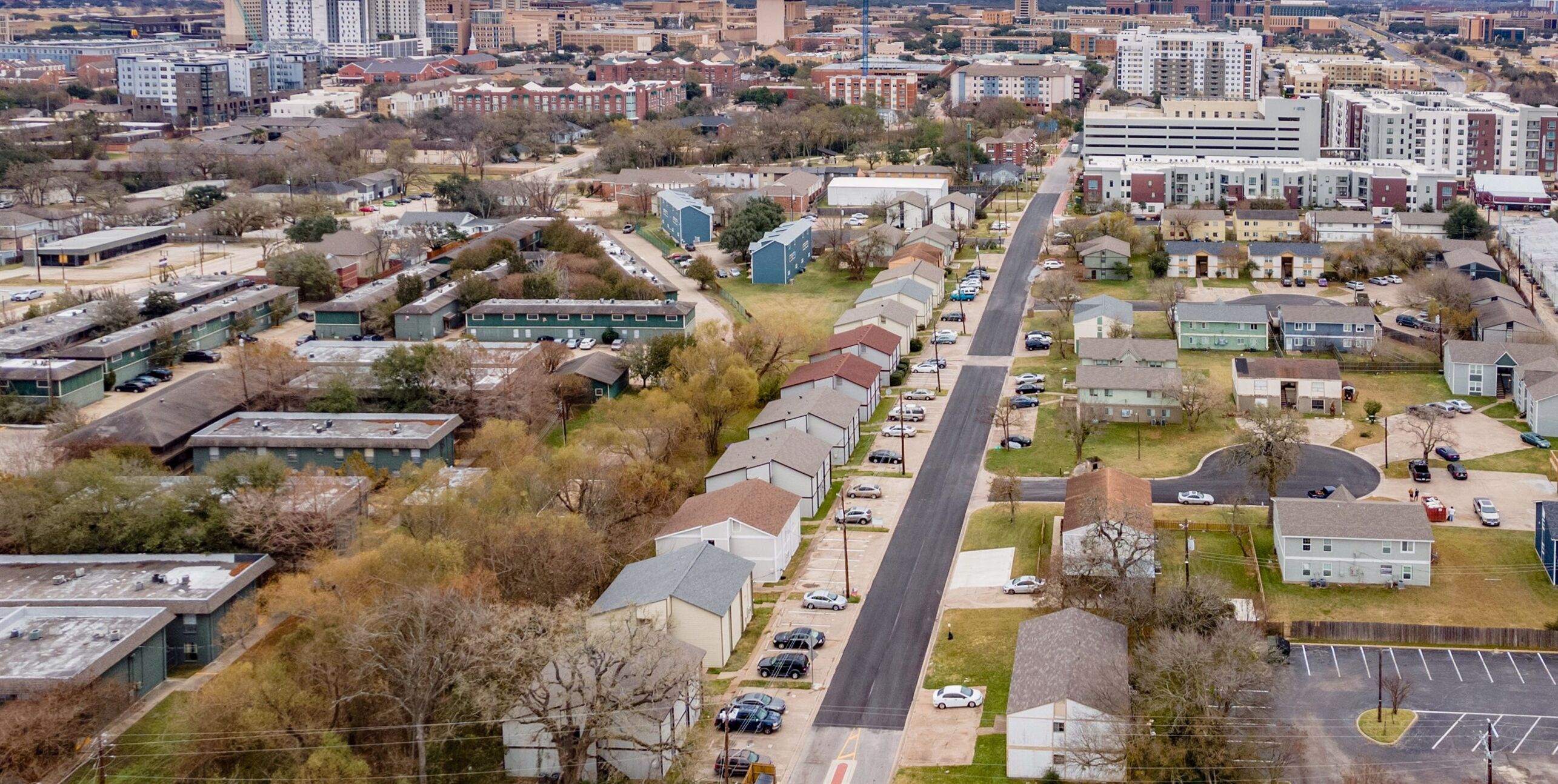 Vista aérea de una zona residencial con una avenida principal, casas y edificios.