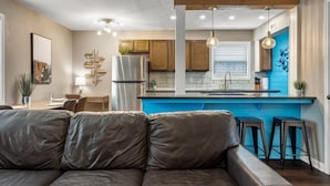 A modern kitchen with a blue countertop, wooden cabinets, and a stainless steel refrigerator. - Kelly's Cove: 1st Flr 2 Bdrm-Walk to A&M-King Beds (Bryan)