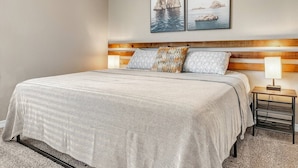 A bedroom with a bed, a nightstand, a lamp, and two framed pictures on the wall. - Kelly's Cove: 1st Flr 2 Bdrm-Walk to A&M-King Beds (Bryan)