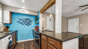A modern kitchen with wooden cabinets, a built-in oven, and a blue accent wall. - Kelly's Cove: 1st Flr 2 Bdrm-Walk to A&M-King Beds (Bryan)