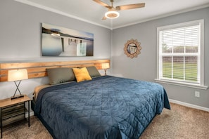 Relax in a serene bedroom with a large bed, wooden headboard, and a nightstand with a lamp.