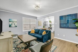 Relax in this stylish living room with a sofa, dining area, and kitchen.