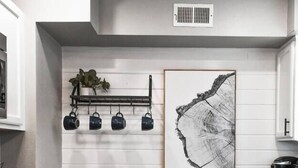 A kitchen with white paneling, a black stove, a trash can, and a coffee maker. - Magnolia Farms: Walk to A&M, Comfy King Beds (Bryan)