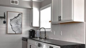 A compact kitchen with a dishwasher, washing machine, and a marble countertop. - Magnolia Farms: Walk to A&M, Comfy King Beds (Bryan)