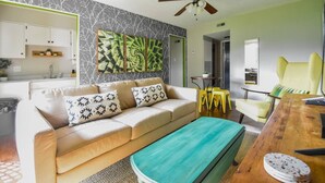 Un salon avec un canapé beige, une table basse en bois et un ventilateur de plafond.