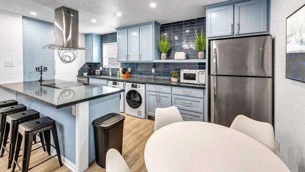 Une cuisine moderne dotée d’un îlot central, d’appareils électroménagers en acier inoxydable et de meubles de couleur bleu clair.
