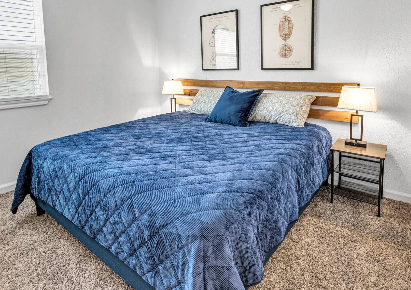 A bedroom with a large bed, two bedside tables with lamps, and two framed certificates on the wall.