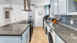Une cuisine moderne dotée de plans de travail en granit, d’appareils électroménagers en acier inoxydable et de meubles de couleur bleu clair.