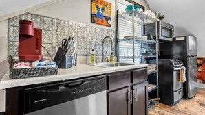 A compact kitchen with a dishwasher, a red coffee maker, and a black oven. - Poppy: Quirky, Walk to A&M, Comfy King Bed, Fun Space (Bryan)