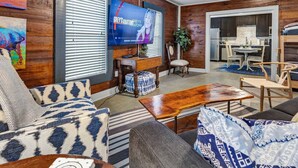 Un salon comprenant un téléviseur, un canapé, une table basse et un coin repas avec des chaises et une table.