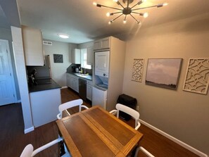 Enjoy meals in this kitchen with oven, microwave, and sink, surrounded by framed artwork and a dining table for two.