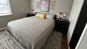 Un dormitorio con cama, mesitas de noche, alfombra y ventilador de techo.