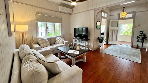A spacious living room with a sofa set, a coffee table, a TV, and a large window.