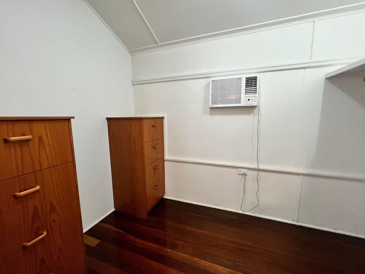 A room with wooden cabinets, a white wall, and a vent.