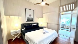 A bedroom with a bed, nightstands, a ceiling fan, and a door leading to a balcony.