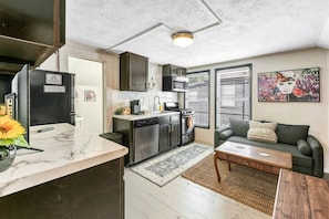 Cozy living space with a kitchenette, sofa, and coffee table, featuring an oven and dishwasher.