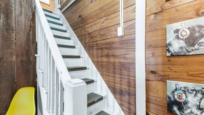 A staircase with white railings and wooden steps, a yellow chair, and two framed artworks on the wall. - Tribeca: So Fun! Walk to A&M, Comfy King Beds (Bryan)