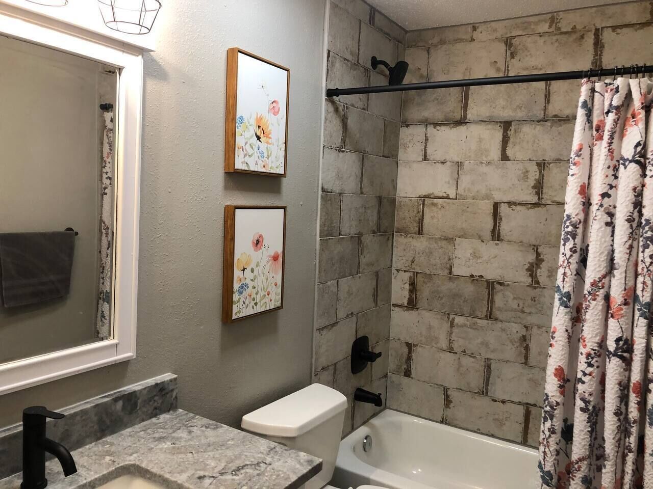 A bathroom with a marble sink, a toilet, a bathtub, and a shower curtain.