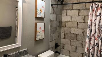 A bathroom with a marble sink, a toilet, a bathtub, and a shower curtain.