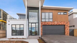 Een modern huis met twee verdiepingen, een garage, grote ramen en een plat dak.