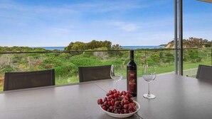 Een tafel met een schaal druiven, een wijnfles en twee wijnglazen op een balkon met uitzicht op een prachtig landschap.