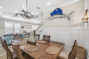A dining area with a wooden table, woven placemats, and a chandelier.
