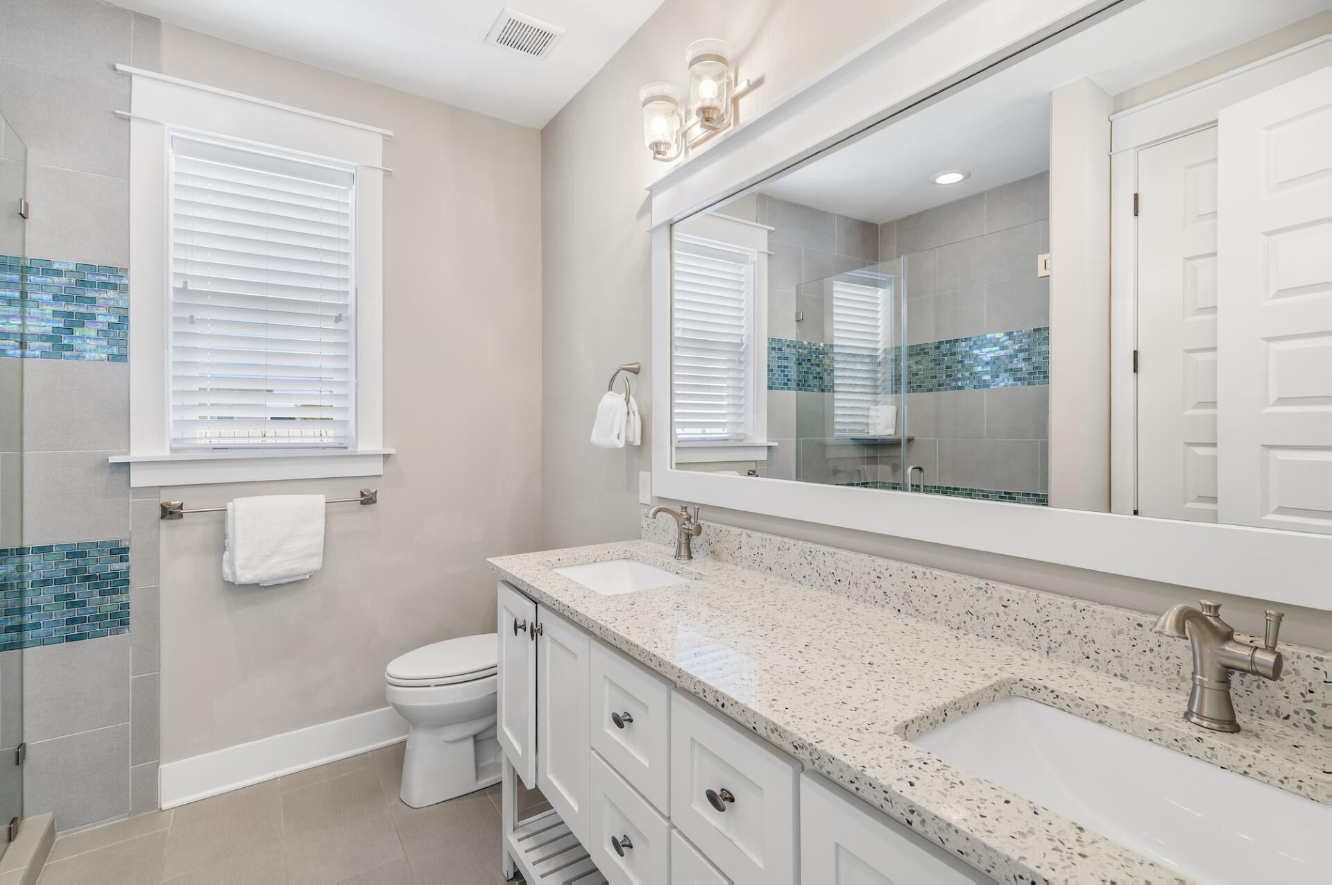 A modern bathroom with a double sink vanity, a large mirror, and a toilet.