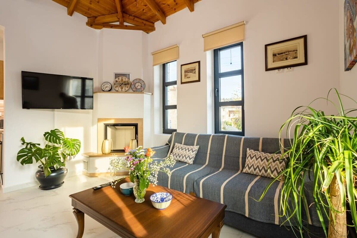 A living room with a sofa, a coffee table, a TV, and a fireplace.