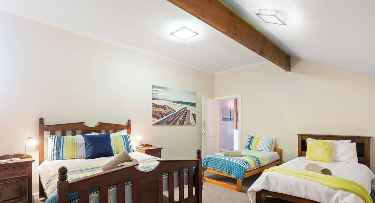A bedroom with two beds, wooden headboards, bedside tables, and a painting on the wall.