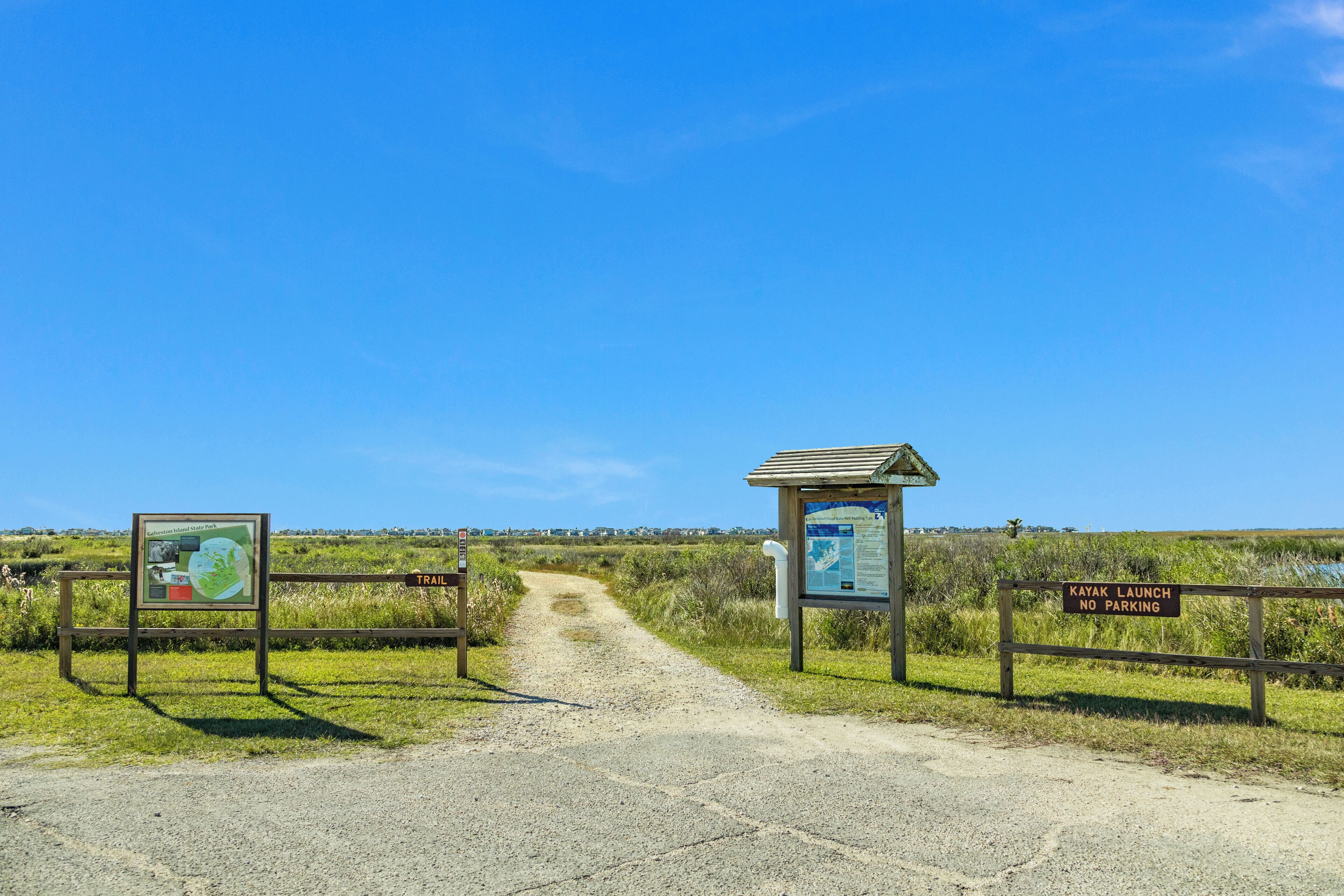 A dirt path leading to a kayak launch area with informational signs.