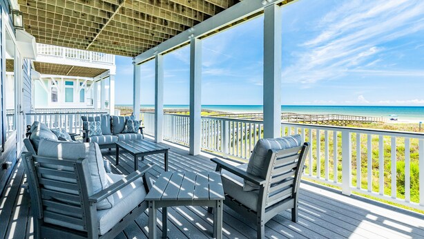 A covered outdoor deck with a view of the beach, featuring a seating area with a table and chairs. - Beachfront Beauty w/ 5 Decks, Private Walkover, Spacious Living Area & Elevator! (Galveston)