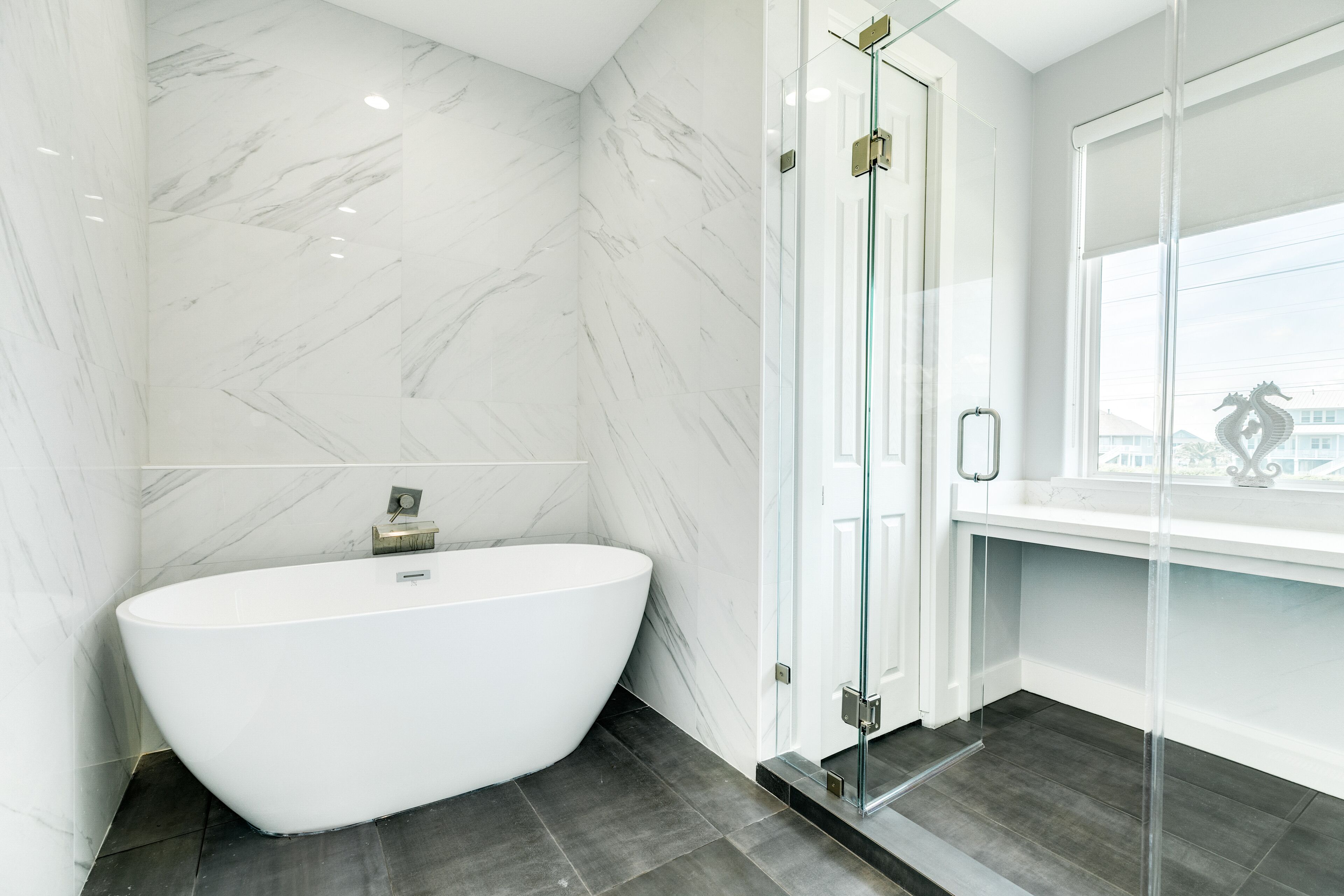 Une salle de bain moderne avec une baignoire sur pieds, une douche à parois de verre et une vue sur la ville par la fenêtre.