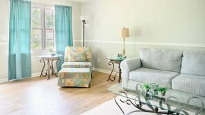 A living room with a sofa, ottoman, and a glass coffee table. - Peaceful 3BR/2BA House Near EVERYTHING w/WIFI  (Dothan)