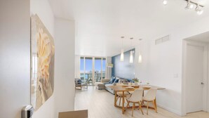Ein modernes Wohnzimmer mit Essbereich, großen Fenstern und Blick auf die Stadt.