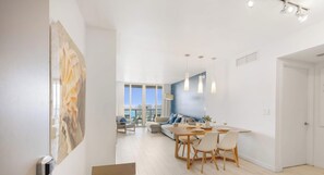 A modern living room with a dining area, large windows, and a view of the city.