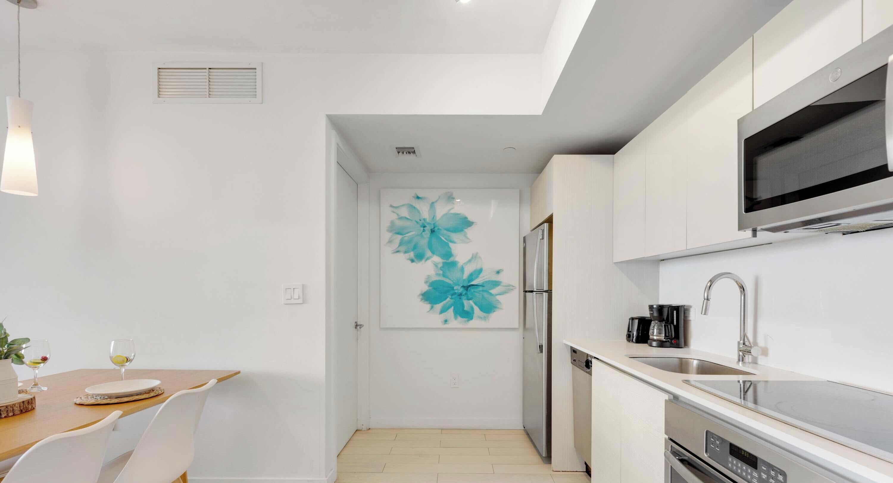 A modern kitchen with a dining area, a large flower mural, and a built-in oven.