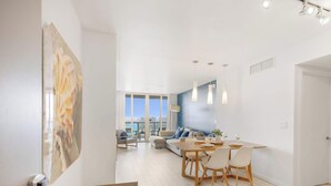Uma sala de estar moderna com área de jantar, janelas amplas e vista para a cidade.