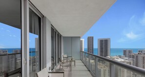 A balcony with a city view, a table, and two chairs. - Upper Apartment + Pool + Gym + Amazing view (Hallandale Beach)