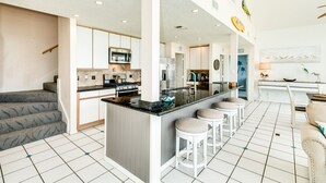 Una cocina moderna con una isla central, armarios blancos y piso de baldosas.