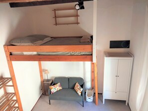 Uma cama beliche com escrivaninha e armário em um quarto pequeno.