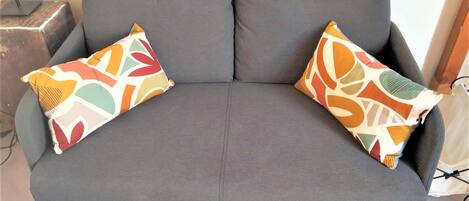 A grey sofa with two colorful patterned pillows.